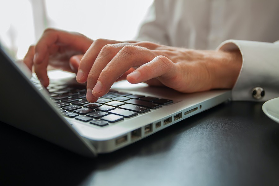 Nahaufnahme von Händen auf einer Laptop-Tastatur bei der Dateneingabe - Symbolbild für die digitale Verarbeitung von Daten im Rahmen der Elektrifizierung des Fuhrparks