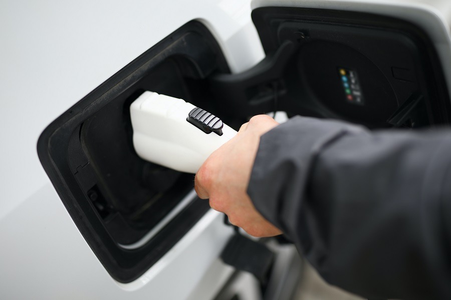 Eine Hand steckt ein Ladekabel in ein Elektroauto. Carano zeigt, wie Unternehmen mit THG Quote Änderungen im Fuhrpark Einnahmen aus elektrischer Mobilität generieren. Die Digitalisierung vereinfacht Abrechnung und Verwaltung und unterstützt eine klimafreundliche Fuhrparkstrategie mit wirtschaftlichem Mehrwert.