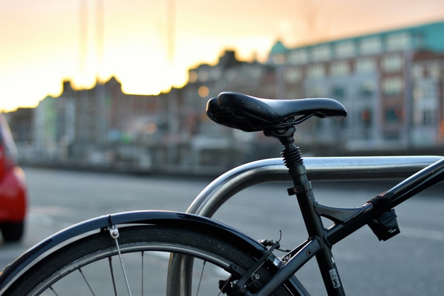 Close-up van een geparkeerde fiets bij een fietsenrek in de stad bij zonsondergang. CarWise ondersteunt bedrijven met digitale oplossingen om fietsen te integreren in mobiliteitsconcepten voor bedrijven. 