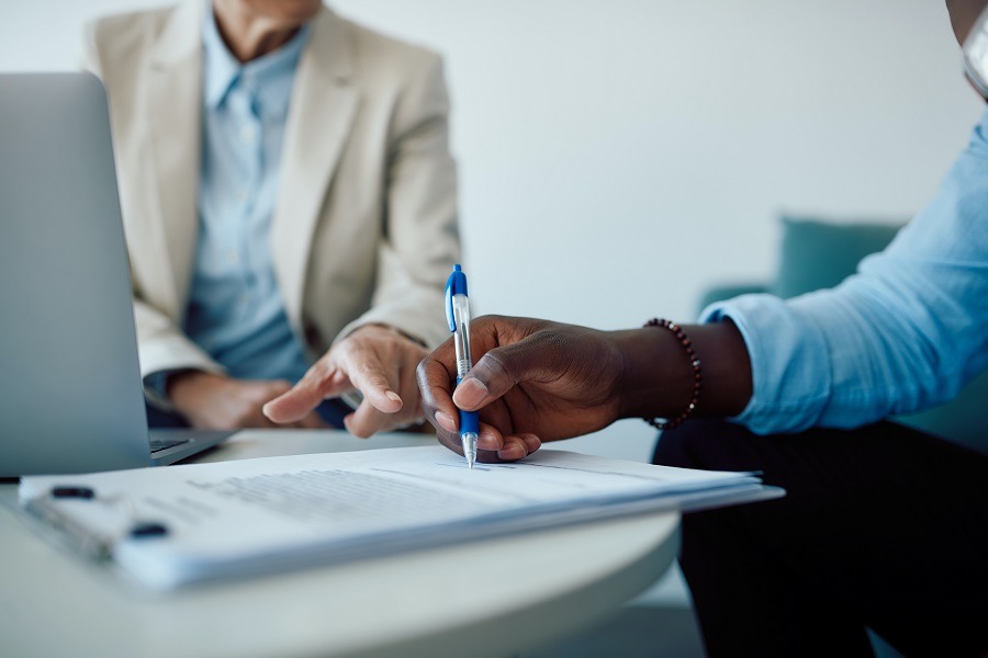 Two people discussing a document at the table, one hand ready to sign. Carano supports companies with digital solutions for pool vehicles and shows when pool vehicles are worthwhile - for legally compliant processes, clear responsibilities and efficient vehicle use in the fleet. 
