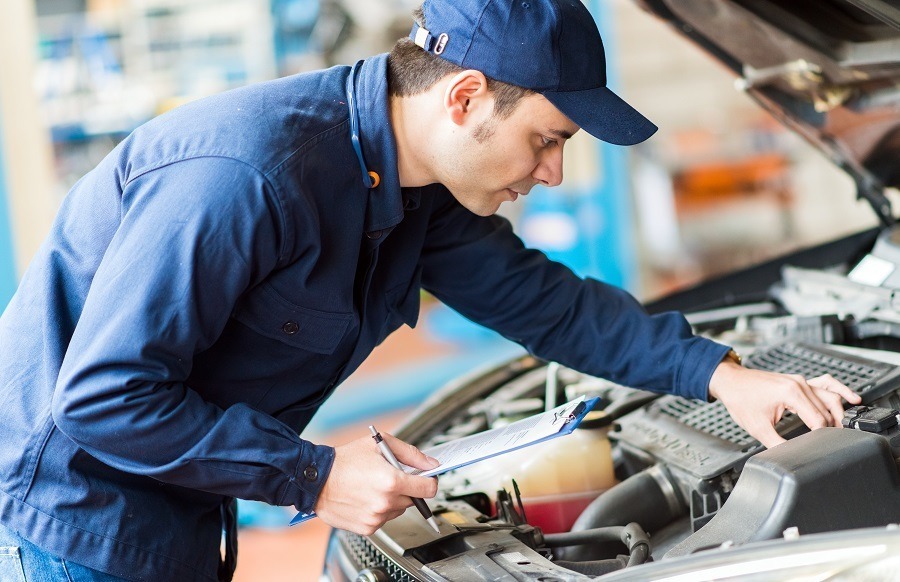 An employee checks the engine compartment of a vehicle and holds a clipboard in his hand. With digital fleet management, Carano makes it easy to organize maintenance and repairs - for greater safety, less downtime and optimized processes in the company fleet.