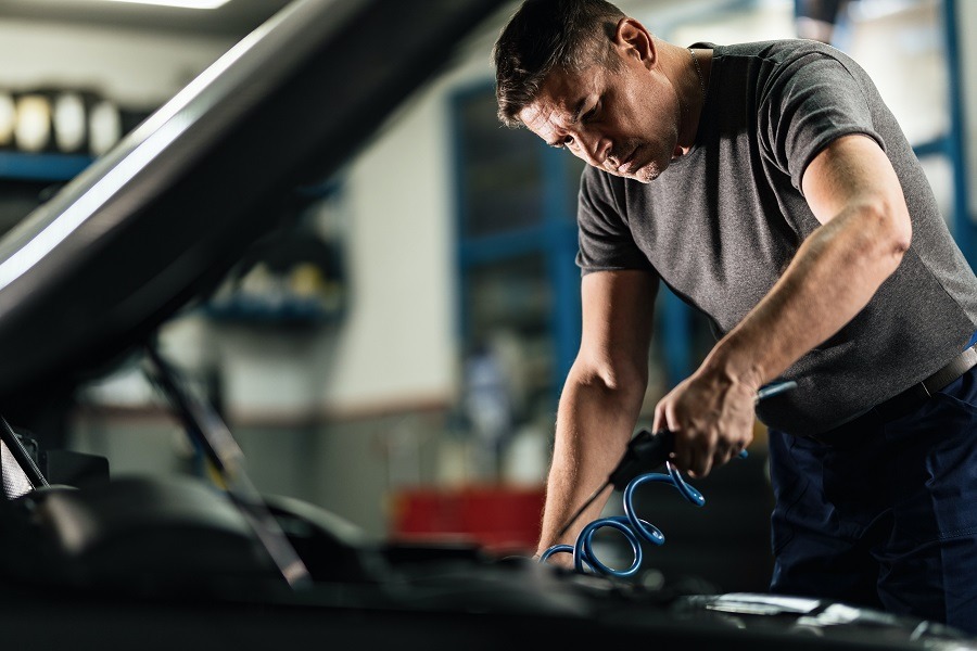 Ein Mann prüft den Motorraum eines Fahrzeugs in der Werkstatt. Mit digitalen Lösungen zeigt Carano Fleet+, ob sich ein E-Auto für den Fuhrpark lohnt.