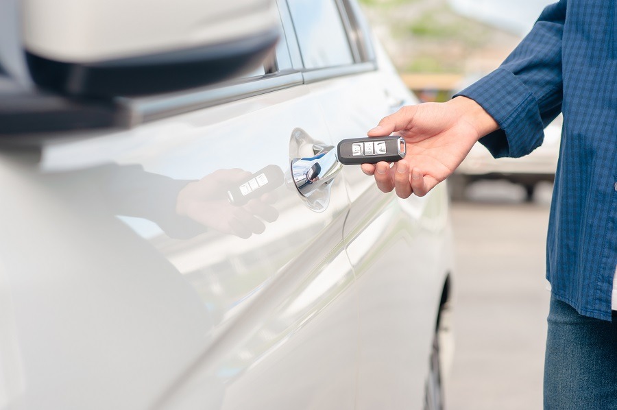 A person uses a car key to unlock the door of a vehicle. Corporate carsharing with CarWise enables simple, digital management of shared company vehicles. 