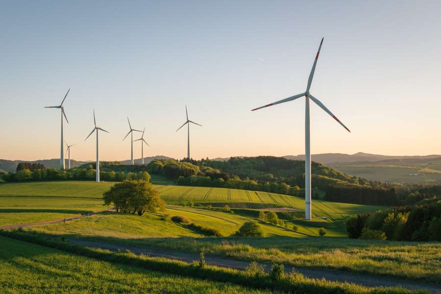 Windkraftanlagen in einer grünen Landschaft – Symbolbild für erneuerbare Energien und die Reduzierung von CO₂-Emissionen