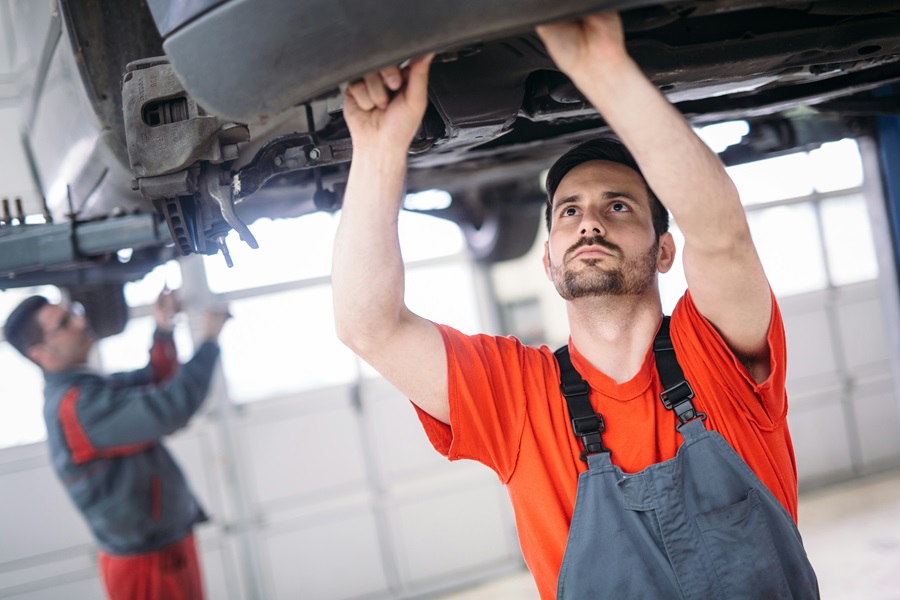 Ein Mechaniker überprüft den Unterboden eines Fahrzeugs in der Werkstatt. Regelmäßige Wartung ist zentral für Sicherheit und Effizienz im Fuhrpark. Carano bietet digitale Lösungen für Wartungsplanung, Schadenmanagement und Fuhrparkorganisation – für einen zuverlässigen, wirtschaftlichen und zukunftsfähigen Fuhrparkbetrieb.