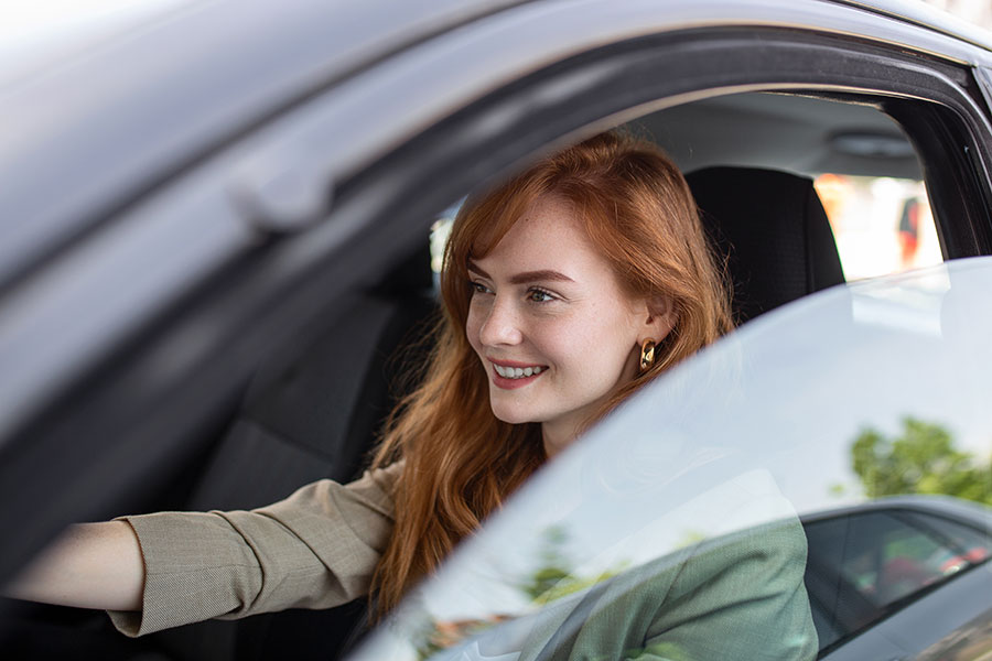 Eine Frau sitzt lächelnd am Steuer eines Autos. Carano bietet digitale Unterstützung bei der Anwendung der ein Prozent Regelung für Dienstwagen. Die Software sorgt für transparente und rechtssichere Berechnungen, erleichtert die Verwaltung und schafft Klarheit für Fahrerinnen und Fuhrparkverantwortliche.