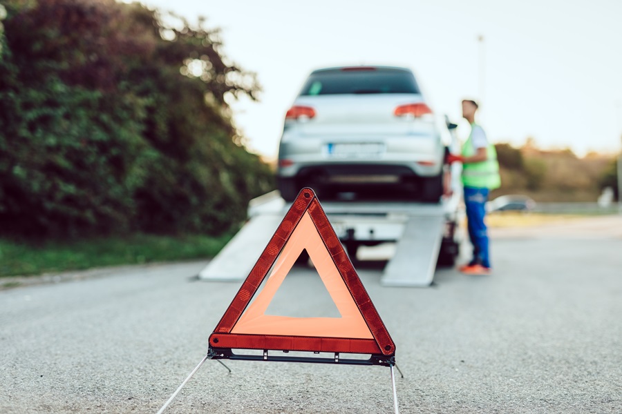 Ein Warnschild steht vor einem Pannenfahrzeug, das auf einen Abschleppwagen geladen wird. CarWise unterstützt Fuhrparkleiter mit zuverlässiger Flottenversicherung und digitalen Lösungen für ein schnelles Schadenmanagement. So bleibt Ihre Fahrzeugflotte mobil, sicher und effizient auch im Ernstfall.