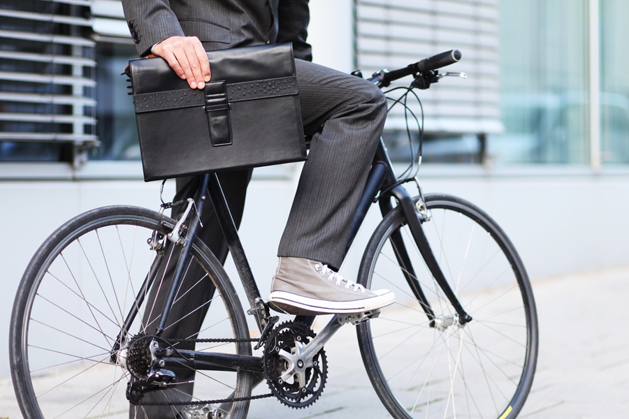 Ein Mann im Anzug sitzt mit Aktentasche auf einem Fahrrad – Symbol für flexible Mobilität im Berufsalltag. Carano Fleet+ bietet digitale Lösungen für modernes Fuhrparkmanagement. Ob Dienstfahrrad oder Auto: Lohnt sich ein Firmenwagen?